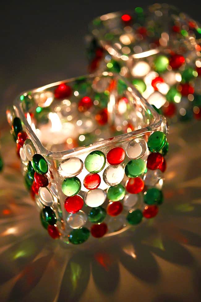 A candle burning and reflecting in a Christmas candle holder