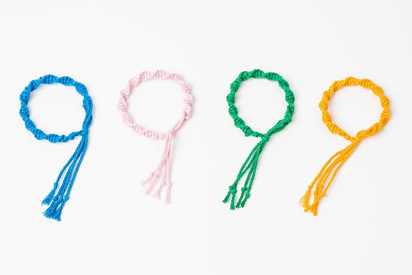 Four macrame bracelets laid out on a white background
