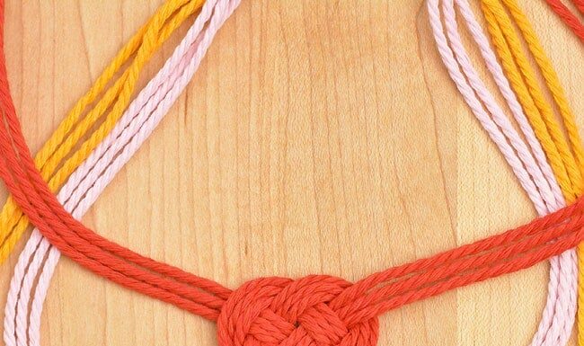 DIY Macrame Necklace Three Celtic heart macrame necklaces on a wooden background