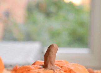 DIY Paper Mache Pumpkins: Step-by-Step Guide Paper mache pumpkin on wood with fall leaves around it