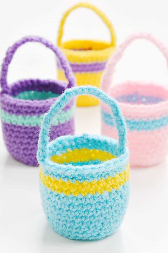 Group of colourful crochet Easter baskets made with a free PDF pattern