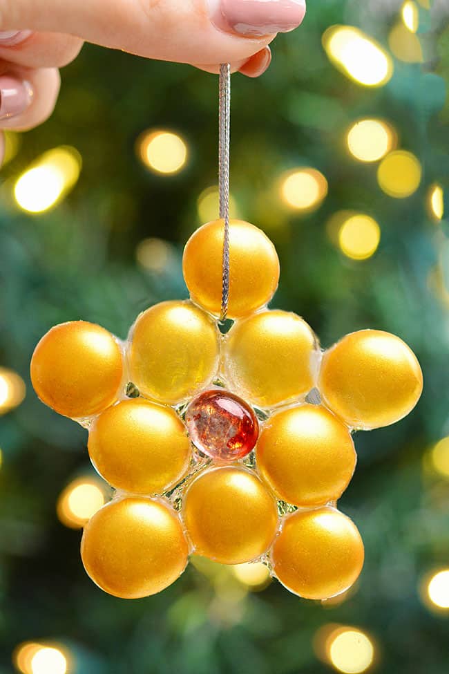 Holding a DIY star ornament in front of the Christmas tree