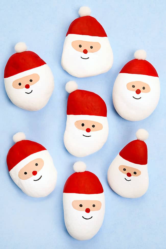 Group of painted Santa rocks on a blue background
