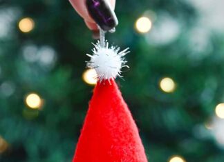 How to Make a Pinecone Gnome Holding a DIY pinecone gnome ornament in front of the Christmas tree