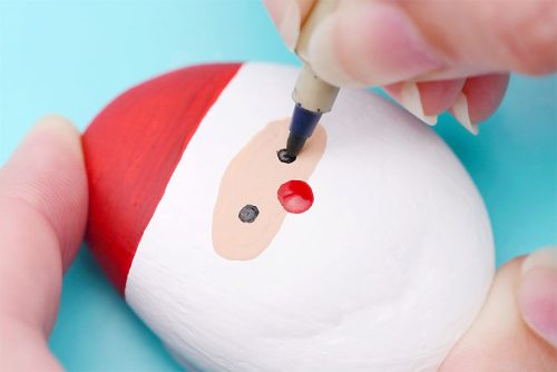 Drawing eyes on rock painted like Santa