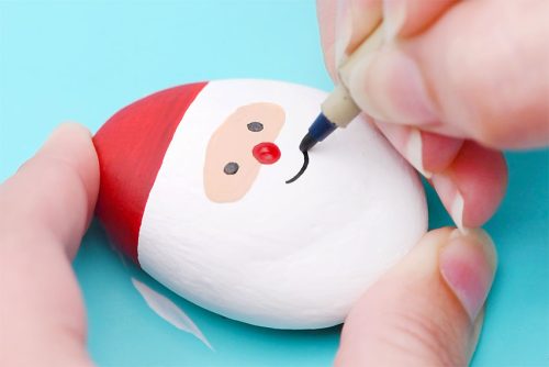 Drawing smile on rock painted like Santa