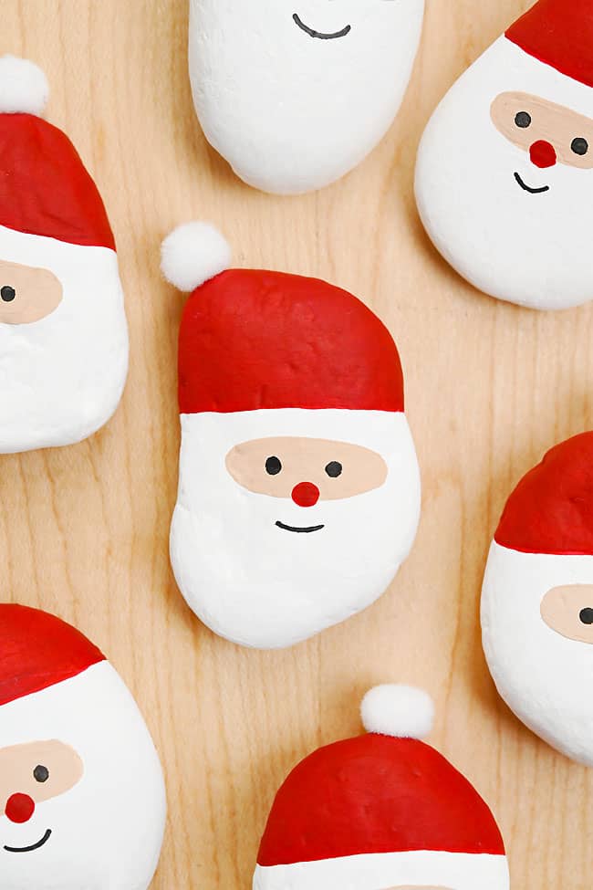 Painted Santa rocks on a wood background