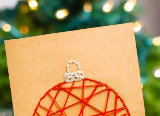 How to Make String Art Christmas Cards String art Christmas card held in front of a Christmas tree
