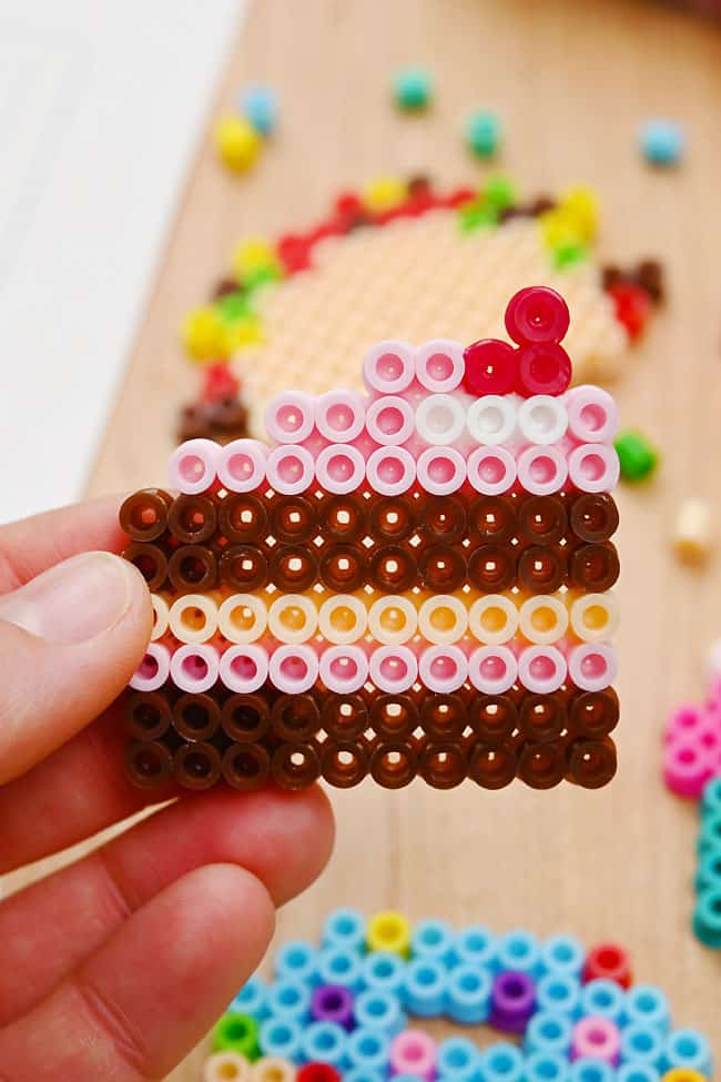 Holding a chocolate cake slice made from Perler beads