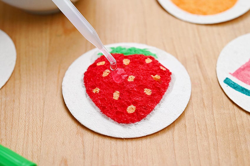 Adding water to a strawberry drawing on sponge paper to make it puffy